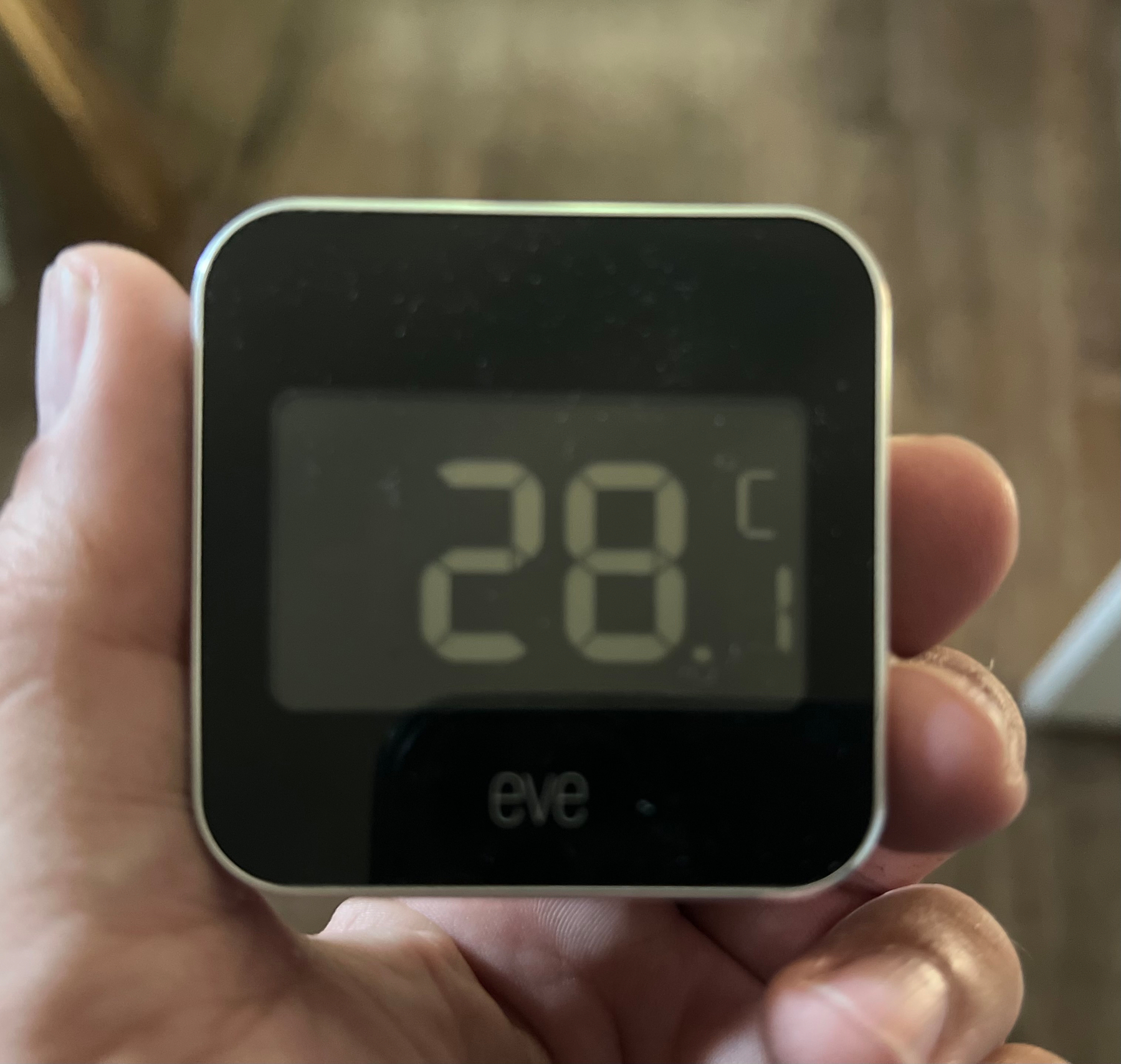 A hand is holding a digital thermometer displaying a temperature of 28.1°C.